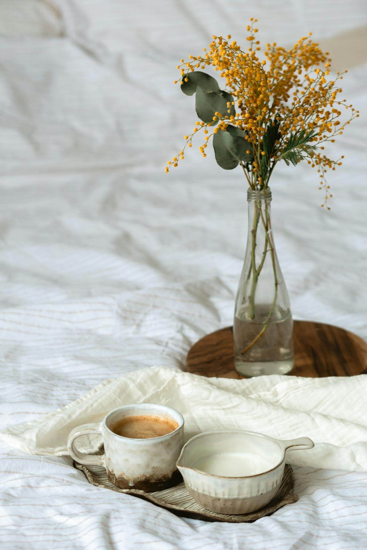 Tasse Kaffee auf einem Bett mit Blumen im Hintergrund – ruhiger Moment im Mama-Alltag zur Beruhigung des Nervensystems