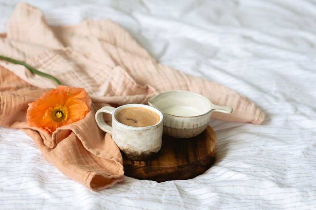 Sanfter Morgenmoment mit Kaffee und Blumen im Bett als Symbol für Ruhe und Selbstfürsorge im Mama-Alltag