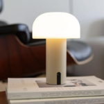 LUUK Tischlampe mit warmem, gedämpftem Licht auf einem Beistelltisch.